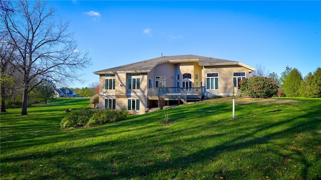 back of house featuring a deck, a lawn, and stucco siding