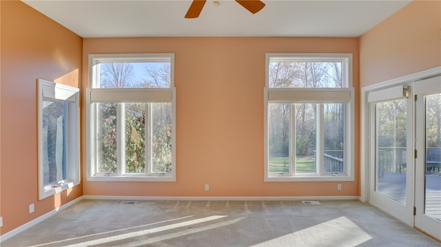 carpeted empty room with visible vents, plenty of natural light, and baseboards