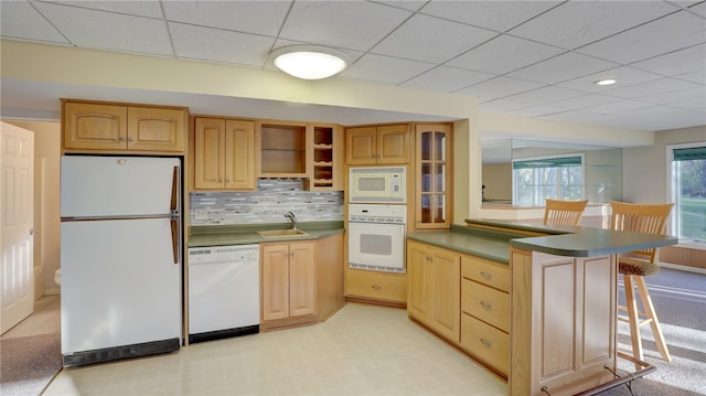 kitchen with a peninsula, white appliances, a breakfast bar, a sink, and open shelves