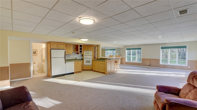 kitchen featuring white appliances, wainscoting, and open floor plan