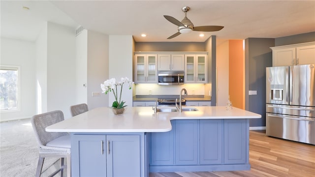 kitchen featuring a kitchen bar, appliances with stainless steel finishes, light countertops, and a sink