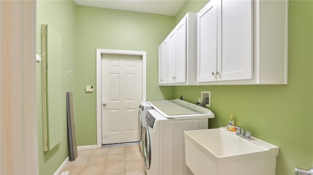 laundry area featuring washing machine and clothes dryer, cabinet space, light tile patterned flooring, a sink, and baseboards