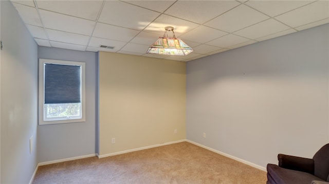 spare room featuring a paneled ceiling, visible vents, and light carpet