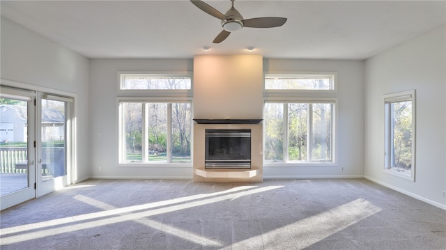 unfurnished living room with baseboards, a tiled fireplace, and carpet flooring