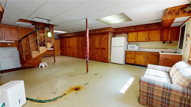 315 W Autumn Dr, Oakwood, IL 61858 - kitchen with washer / clothes dryer, white appliances, brown cabinetry, light countertops, and wood walls