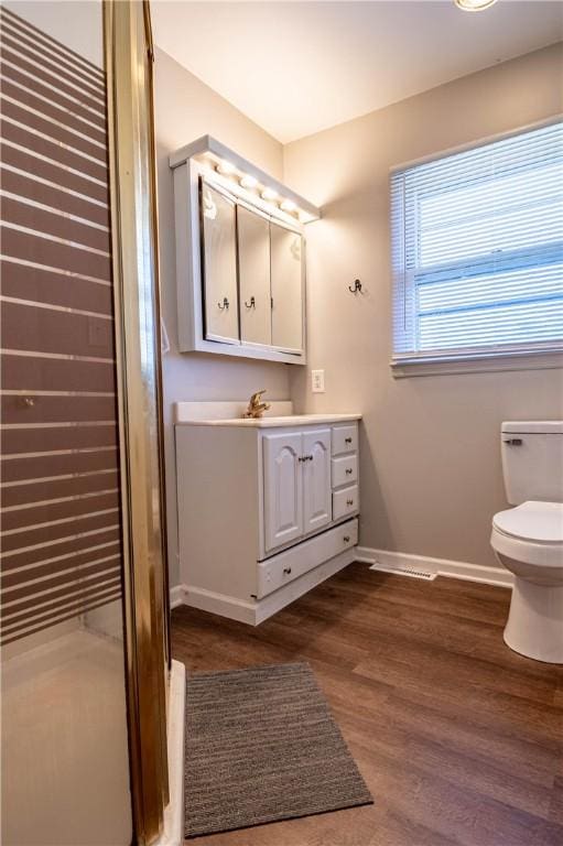 bathroom featuring baseboards, toilet, wood finished floors, and vanity