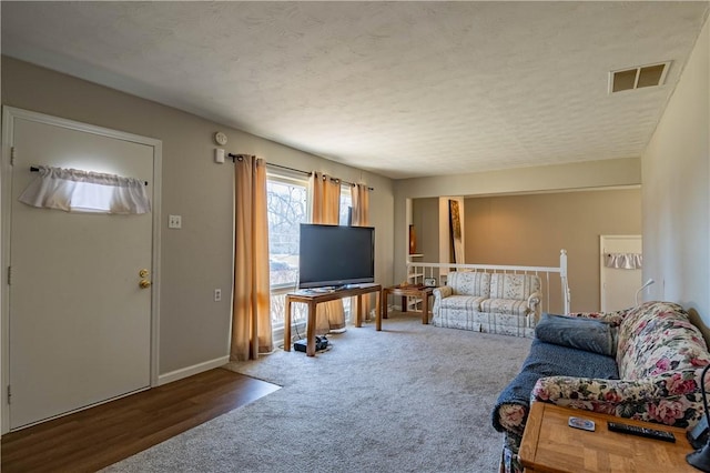 living room with carpet flooring, baseboards, visible vents, and a textured ceiling