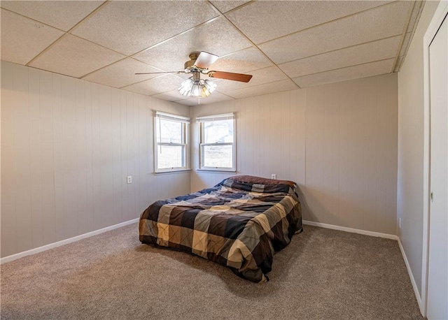 bedroom featuring carpet, baseboards, a drop ceiling, and ceiling fan