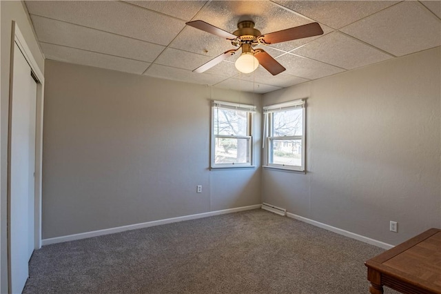 unfurnished bedroom with a drop ceiling, ceiling fan, baseboards, and carpet floors