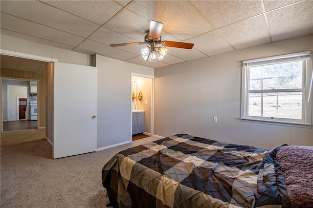 carpeted bedroom featuring a drop ceiling, baseboards, and a ceiling fan