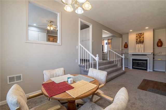 carpeted dining space with visible vents, baseboards, stairway, recessed lighting, and a glass covered fireplace