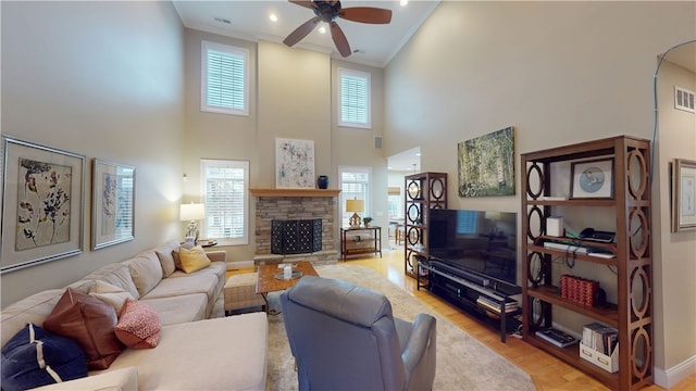 living room with crown molding, a fireplace, light hardwood / wood-style floors, and ceiling fan