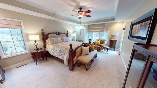 carpeted bedroom with a tray ceiling, ornamental molding, and ceiling fan