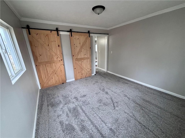 unfurnished bedroom with a barn door, baseboards, carpet flooring, and ornamental molding