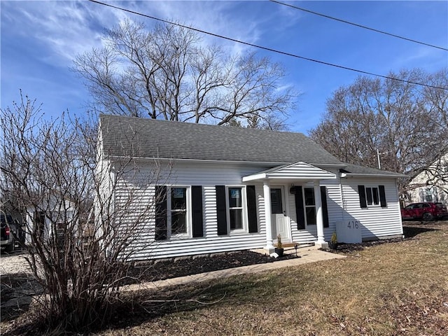 bungalow-style house featuring roof with shingles and a front yard