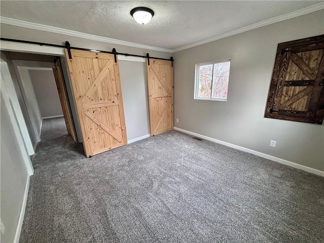 unfurnished bedroom with crown molding, a barn door, carpet, and baseboards