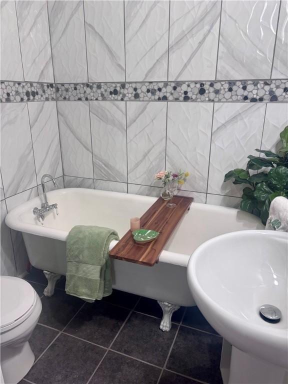 full bath with a freestanding bath, tile walls, toilet, and tile patterned floors