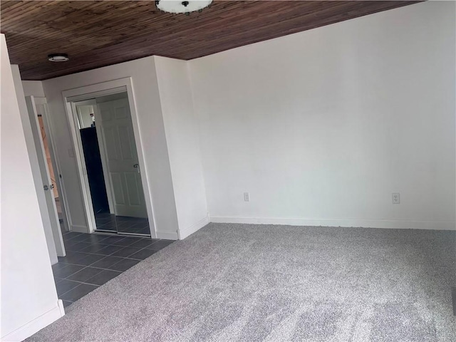 spare room with dark tile patterned flooring, dark carpet, wood ceiling, and baseboards