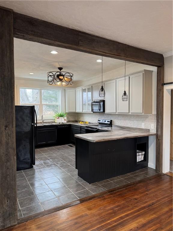 kitchen with black appliances, a peninsula, beam ceiling, and decorative backsplash