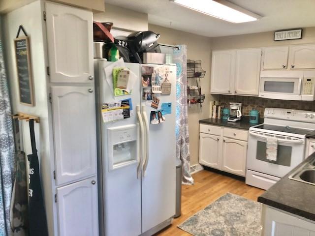 1213 Collins Dr, Effingham, IL 62401 - kitchen with white appliances, dark countertops, white cabinets, and light wood-type flooring