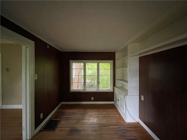 unfurnished bedroom with a textured ceiling and dark hardwood / wood-style flooring