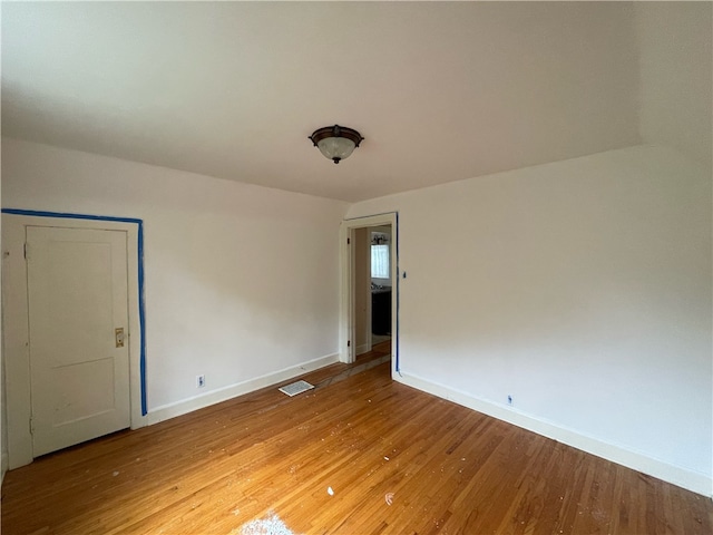 unfurnished room featuring light wood-type flooring and vaulted ceiling