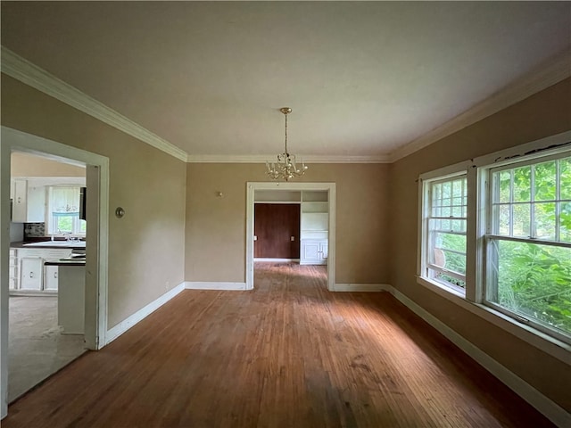 unfurnished dining area featuring crown molding, dark wood-type flooring, a chandelier, and sink