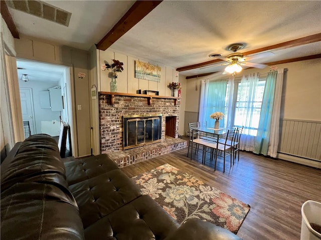 living room featuring beam ceiling, ceiling fan, a fireplace, and hardwood / wood-style flooring