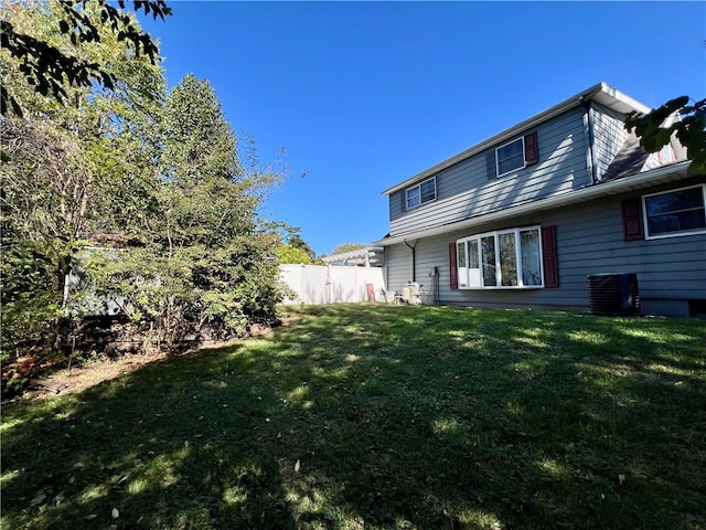 rear view of property featuring a lawn and central AC