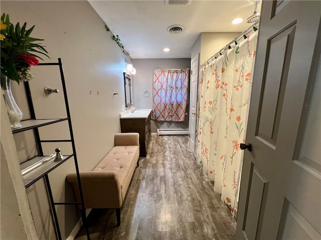 bathroom featuring a shower with shower curtain, hardwood / wood-style floors, vanity, and a baseboard radiator