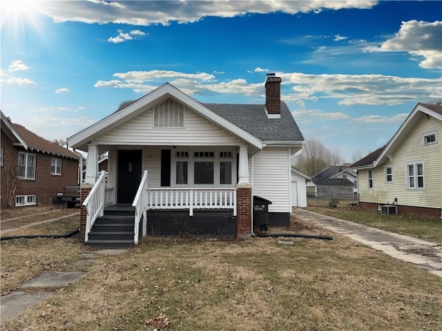 bungalow-style home with a front yard, central air condition unit, and covered porch