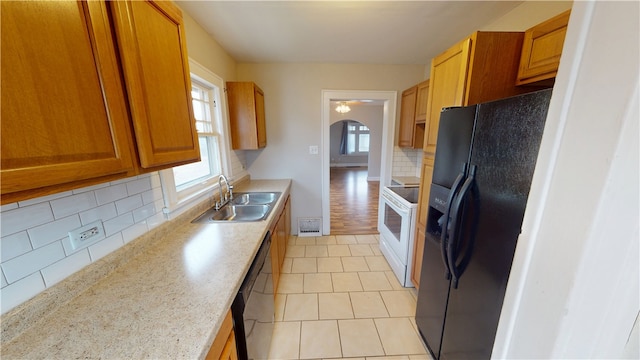 kitchen featuring light tile patterned flooring, sink, decorative backsplash, and black appliances