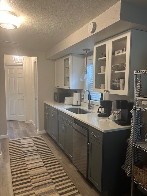 3221 E Lake Paradise Rd, Mattoon, IL 61938 - kitchen with a textured ceiling, wood finished floors, light countertops, stainless steel dishwasher, and glass insert cabinets
