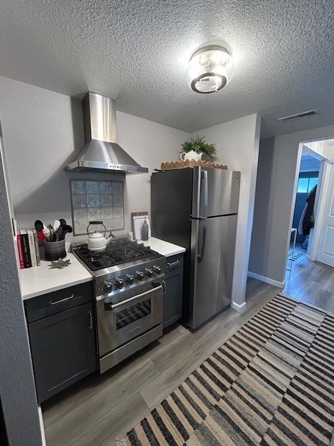 3221 E Lake Paradise Rd, Mattoon, IL 61938 - kitchen featuring stainless steel appliances, wall chimney exhaust hood, light wood-style flooring, a textured ceiling, and light countertops