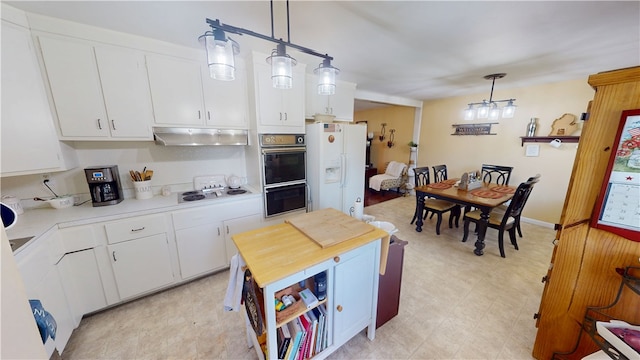 602 Maple Dr, Catlin, IL 61817 - kitchen featuring under cabinet range hood, white cabinets, light flooring, hanging light fixtures, and electric cooktop