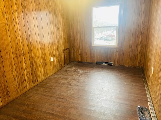 spare room featuring dark hardwood / wood-style floors and wood walls