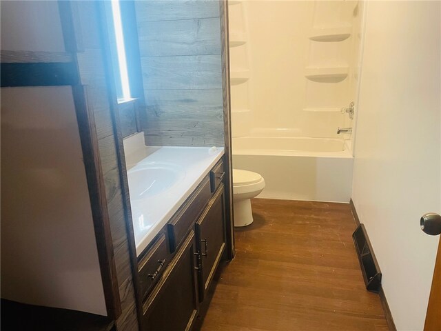 full bathroom with hardwood / wood-style flooring, vanity, toilet, and washtub / shower combination