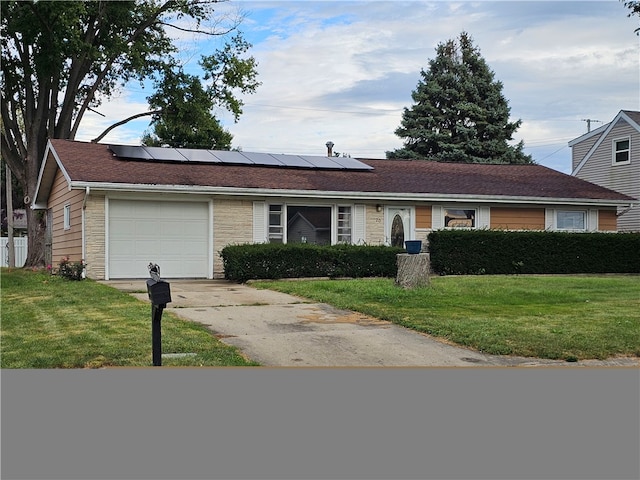 ranch-style house featuring a front yard, solar panels, and a garage