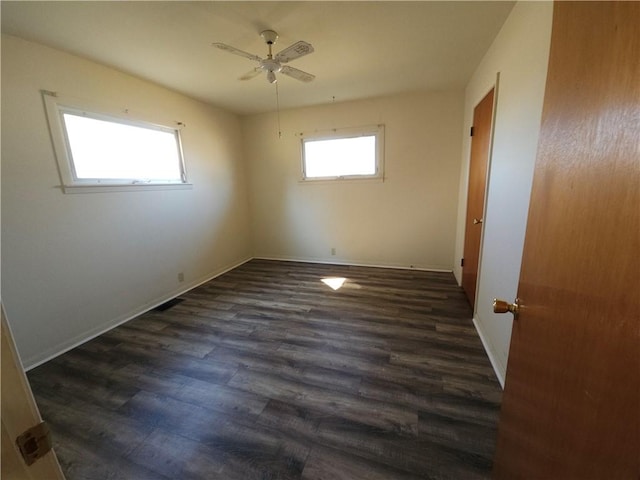 spare room featuring ceiling fan, dark wood-type flooring, and baseboards