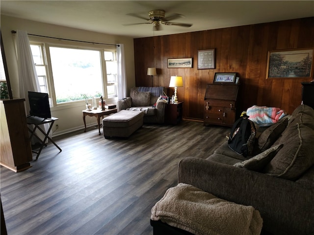 living room with dark hardwood / wood-style flooring, ceiling fan, and wooden walls