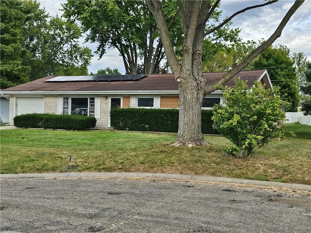 ranch-style house featuring a front lawn, a garage, and solar panels