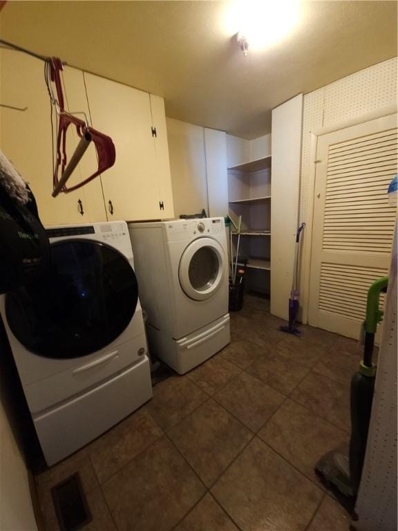 washroom with cabinet space, dark tile patterned floors, and separate washer and dryer