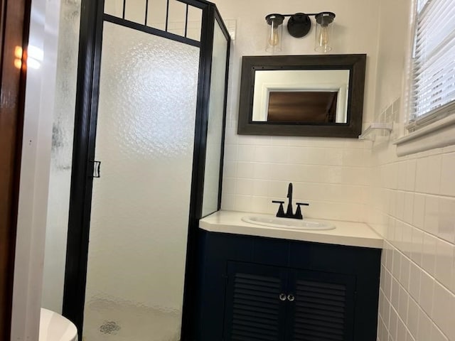 bathroom with vanity, toilet, an enclosed shower, and tile walls