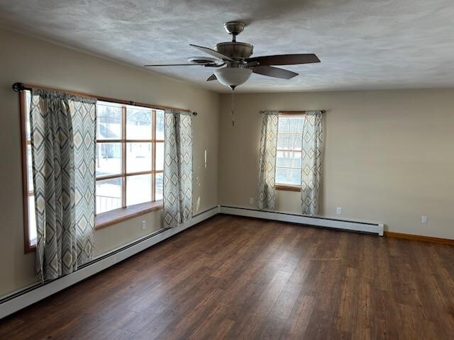 empty room featuring baseboard heating, ceiling fan, and dark hardwood / wood-style floors