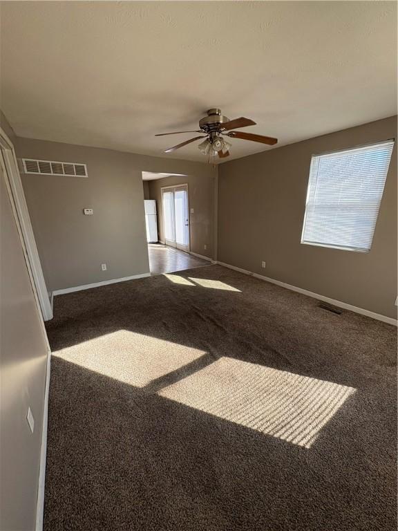 unfurnished room with dark carpet and baseboards