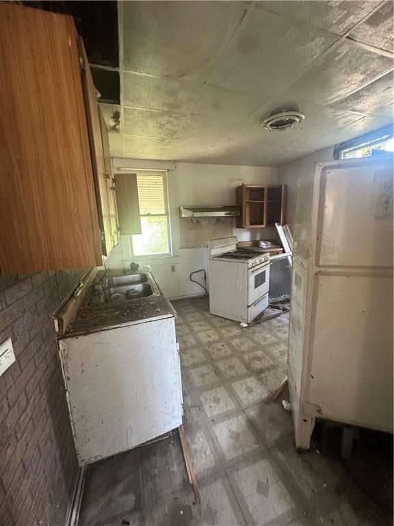 415 W Green St, Decatur, IL 62522 - kitchen featuring gas range gas stove, light floors, a sink, open shelves, and brown cabinetry