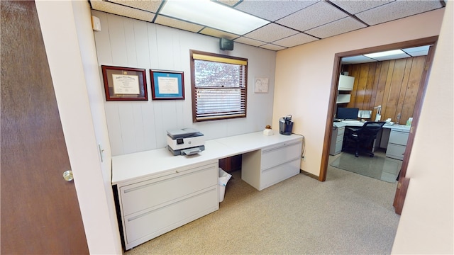 office space with light carpet, a paneled ceiling, and wooden walls