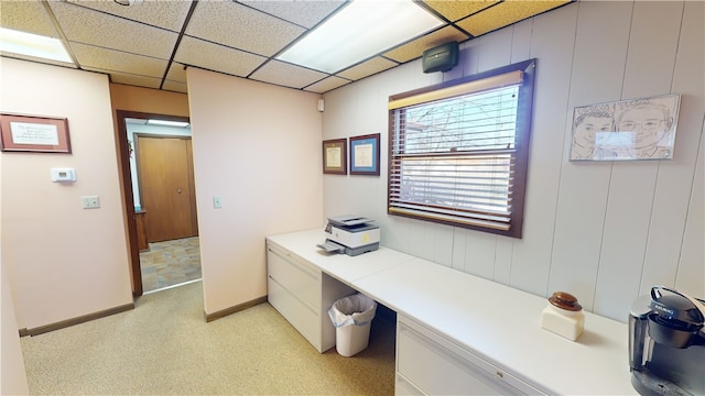 office featuring a paneled ceiling, light colored carpet, and built in desk