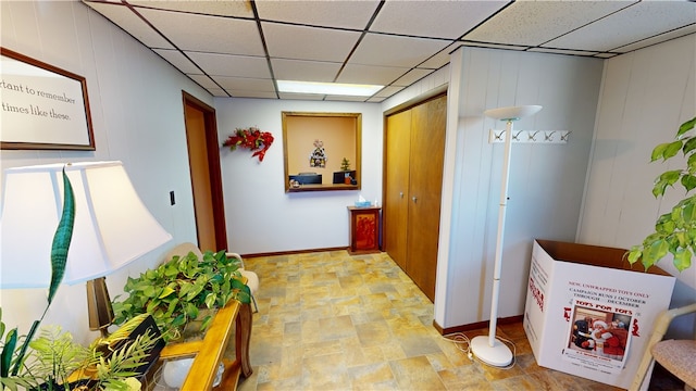 hallway with a drop ceiling and wood walls