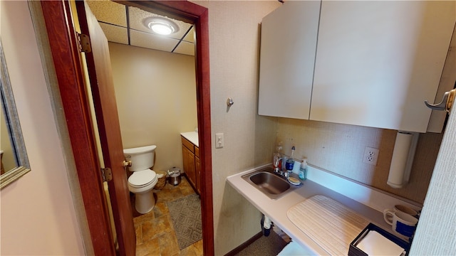 bathroom featuring a drop ceiling, toilet, and vanity